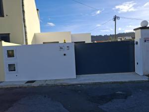 een witte poort met een blauwe muur naast een gebouw bij C&A Guest House in Furnas