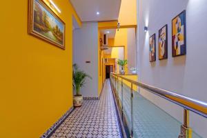 a hallway in a building with yellow walls and a staircase at FabHotel Martine's Residency - French Colony, 5 Mins from Rock Beach in Puducherry
