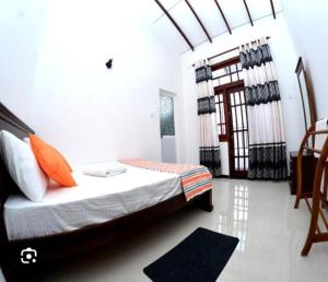 ein Schlafzimmer mit einem Bett mit orangefarbenen Kissen in der Unterkunft madurasinghe villa in Anuradhapura