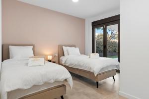 due letti in una stanza bianca con una finestra di Luxury 3BR Garden Apartment Estepona a Estepona Altre 18 foto