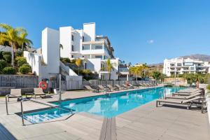 una piscina con sedie a sdraio di fronte a un edificio di Luxury 3BR Garden Apartment Estepona a Estepona