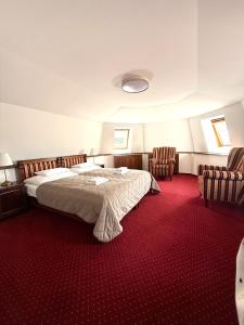 a bedroom with a large bed and two chairs at Zámocká koruna u Hoffera in Nitra