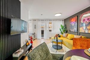 a living room with a yellow couch and a tv at Goldstadt Fancy Apartment in Pforzheim