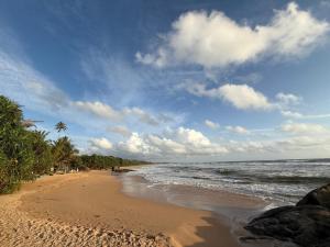 a beach with people walking on the sand and the ocean at New Star Villa in Bentota