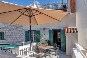 マカルスカにあるVilla Old Town Centre Makarska - Makarska Exklusivの傘とテーブルと椅子のあるパティオ