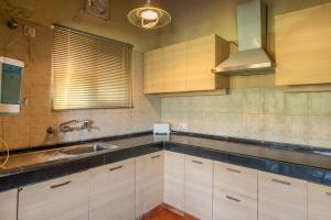 een keuken met witte kasten, een gootsteen en een raam bij Wild Thyme - Levitate at Ramgarh by Roamhome in Rāmgarh