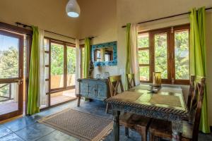 een eetkamer met een houten tafel en ramen bij Wild Thyme - Levitate at Ramgarh by Roamhome in Rāmgarh +33 foto's