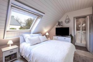 a bedroom with a white bed and a window at L'écrin de bois -sauna - spa in Mur-de-Bretagne