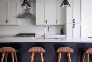 una cucina con armadi bianchi, lavandino e sgabelli di Blue Mountain Townhome - Patio Shuttle Trails a Collingwood