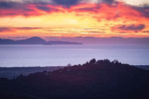 a sunset over the ocean with mountains in the distance at Be Vedetta - Relais & Glamping - Adult Only in Scarlino