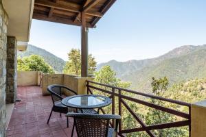 een balkon met een tafel en stoelen en bergen bij Wild Thyme - Levitate at Ramgarh by Roamhome in Rāmgarh