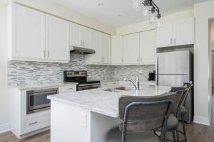 eine Küche mit weißen Schränken und einer Marmoroberfläche in der Unterkunft Luxury Mountain Townhome - Shuttle Patio & Trails in Collingwood