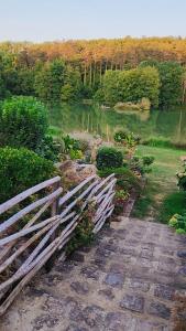 ein Holzzaun neben einem Weg neben einem Teich in der Unterkunft Chambres d'hôtes du Lac Beausoleil in Campsegret