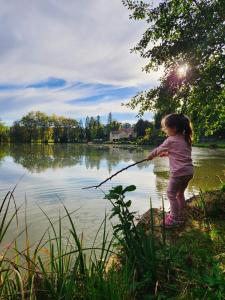 CampsegretChambres d'hôtes du Lac Beausoleil的一个小女孩在水里玩棍子。
