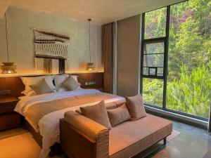 een slaapkamer met een bed, een bank en ramen bij LongSen Valley Inn in Zhukeng +128 foto's