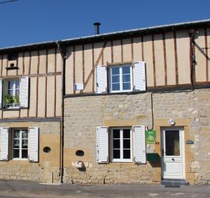 un edificio in pietra con finestre con persiane bianche e una porta di Chez adele a Bouvellemont