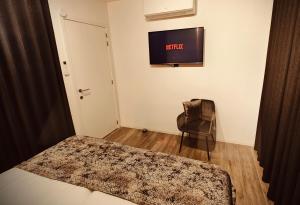 ein Schlafzimmer mit einem Bett und einem Stuhl und einem Fernseher in der Unterkunft De Konik in Uikhoven