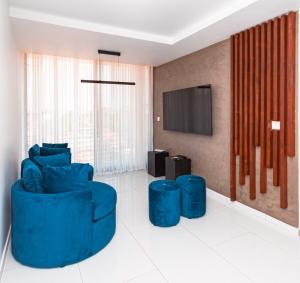 a living room with blue chairs and a flat screen tv at Golf View Apartments- AP1 in Maputo