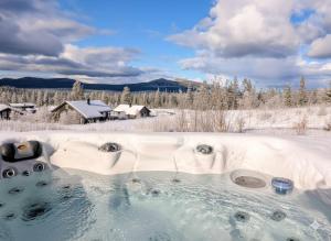 a hot tub in the snow with a house in the background at Winter cabin with Jacuzzi in Vestby +15 photos