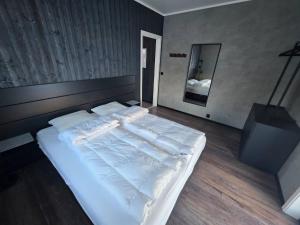a large white bed in a bedroom with a mirror at Winter cabin with Jacuzzi in Vestby