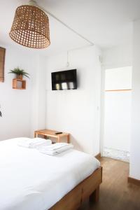 a white bedroom with a bed and a tv on the wall at Latas Surf Lodge in Loredo