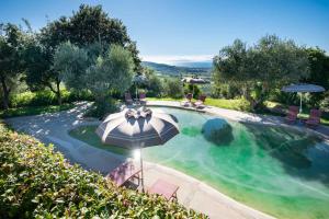 an outdoor swimming pool with an umbrella and chairs at Be Vedetta - Relais & Glamping - Adult Only in Scarlino
