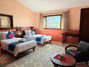 ein Hotelzimmer mit zwei Betten und einem Stuhl in der Unterkunft Ha Giang Aya Lodge by Localvietnam in Dồng Văn