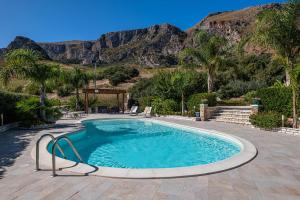 a swimming pool with a mountain in the background at Villa Torre del Mare in Scopello