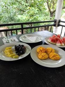 KiriwalagamaFeelATHome STAY - Near sinharajaya的桌子上摆着四盘食物，其中还有水果。