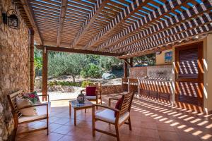 a patio with a wooden pergola and a table and chairs at Villa Torre del Mare in Scopello