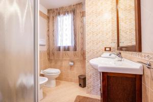 a bathroom with a sink and a toilet and a window at Villa Torre del Mare in Scopello +29 photos