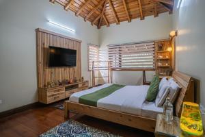 a bedroom with a bed and a flat screen tv at ELIVAAS Tapovan Estate 2-BHK With Kids Attic, Garden, Gazebo and Scenic Views in Bhowāli