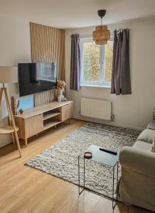Una sala de estar con un sofá y un televisor en Welcome Home, en Royston