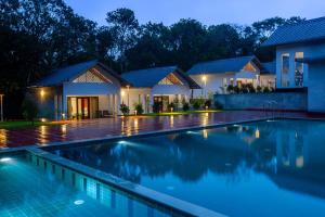 提喀迪Cardamom Village Hill Resort by EGH的夜晚房子前的游泳池