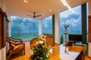 提喀迪Cardamom Village Hill Resort by EGH的客厅配有书桌和鲜花桌