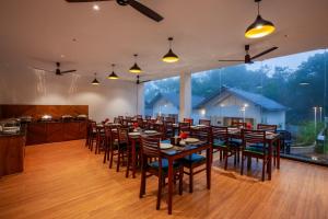 提喀迪Cardamom Village Hill Resort by EGH的有一张长桌子和椅子的餐厅