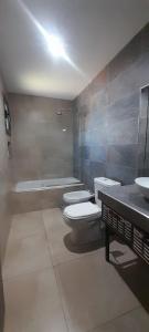 een badkamer met 3 toiletten, een wastafel en een bad bij Casa El Almendro-Barrio Privado - Para 2 personas in Ciudad Lujan de Cuyo