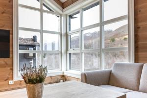 ein Wohnzimmer mit einem Tisch und großen Fenstern in der Unterkunft Stranda Fjellgrend 3 bedrooms and loft - 80C in Stranda