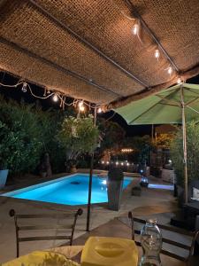 un patio con mesa, sombrilla y piscina en La Papaline de Caroline, en Saint-Saturnin-lès-Avignon