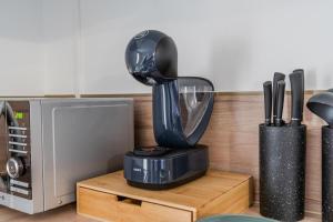 Ein schwarzer Mixer steht auf einem Holzständer neben einer Mikrowelle. in der Unterkunft F2, near Disney in Guérard + 3 Fotos