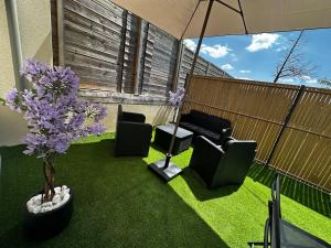 eine Terrasse mit Stühlen, einem Sonnenschirm und Blumen in der Unterkunft F2, near Disney in Guérard