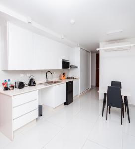 a white kitchen with a sink and a table at Golf View Apartments- AP2 in Maputo +12 photos