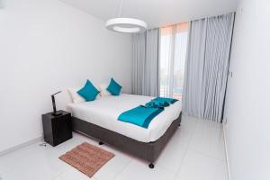 a white bedroom with a bed and a large window at Golf View Apartments- AP2 in Maputo