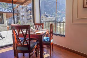 a dining room table with chairs and a large window at Carom Hotel Manali in Manāli