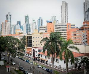 a city street with palm trees in front of a city at Hotel Latino in Panama City