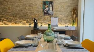 einen Tisch mit einer Flasche Wein sowie Teller und Gläser in der Unterkunft Gîte L'Écrin - Maison de charme 8Pers - By Primo in Buxy + 21 Fotos