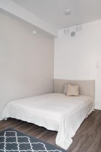 a white bedroom with a bed in a room at Modern Studio Apt in Design District in Helsinki