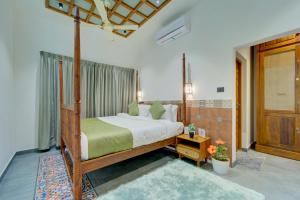 Breeze and Grains Resort 3-BHK Villa with Verandah & Outdoor Patio في Champakulam: غرفة نوم مع سرير بمظلة في الغرفة
