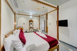 Breeze and Grains Resort 3-BHK Villa with Verandah & Outdoor Patio في Champakulam: غرفة نوم بسرير كبير مع وسائد حمراء وبيضاء