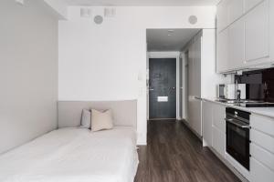 a small white bedroom with a bed and a kitchen at Modern Studio Apt in Design District in Helsinki +13 photos